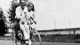 Romy Schneider sitzt mit Michel Piccoli auf dem Fahrrad, im Hintergrund Landschaft
