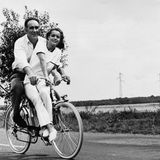 Romy Schneider sitzt mit Michel Piccoli auf dem Fahrrad, im Hintergrund Landschaft