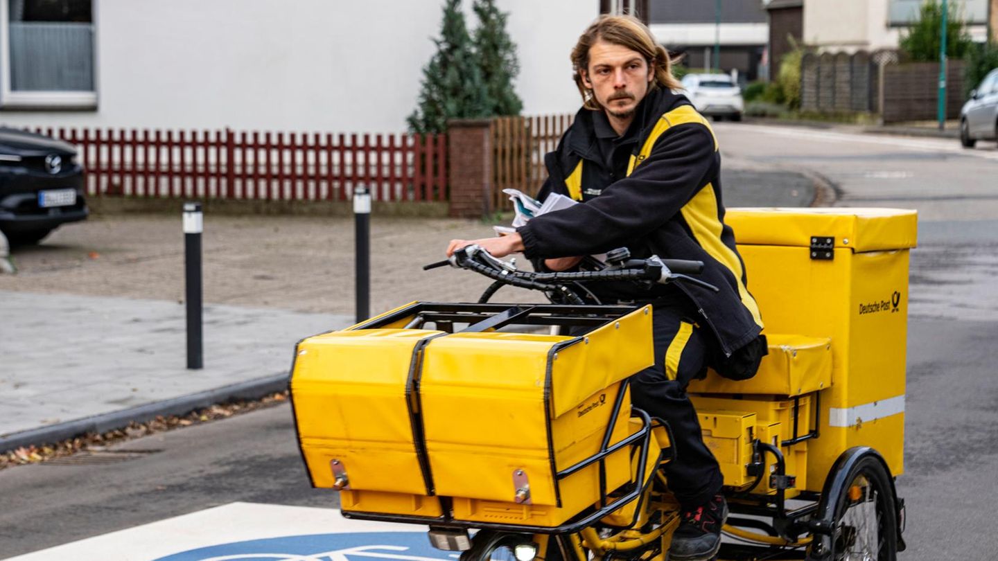 Briefträger fährt die Post auf dem dreirädrigen Lastenfahrrad aus Briefträger fährt die Post auf dem dreirädrigen Lastenfahrrad aus
