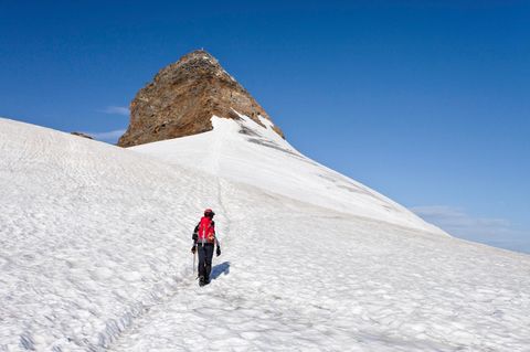 Ein Bergsteiger geht über ein Schneefeld auf den Gipfel des Zuckerhütl in Tirol, Österreich, zu