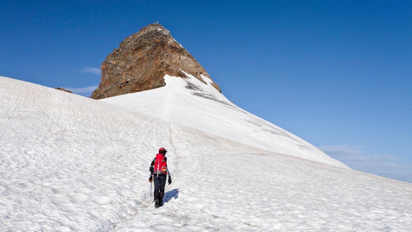 Ein Bergsteiger geht über ein Schneefeld auf den Gipfel des Zuckerhütl in Tirol, Österreich, zu