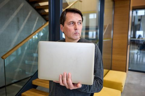 Mobbing im Job Mann mit Laptop guckt misstrauisch