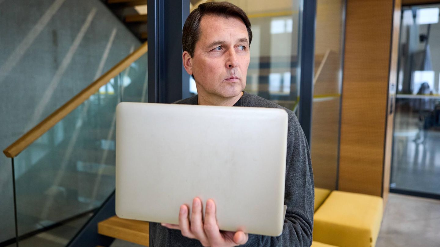Mobbing im Job Mann mit Laptop guckt misstrauisch