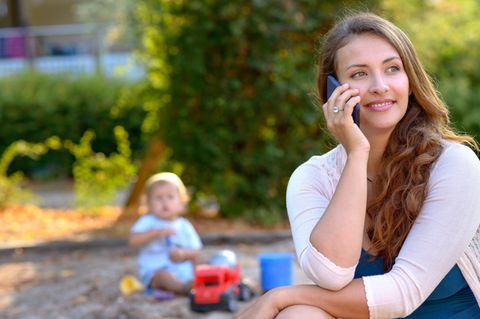 Eine Mutter telefoniert auf dem Spielplatz und sieht ihr Kind nicht