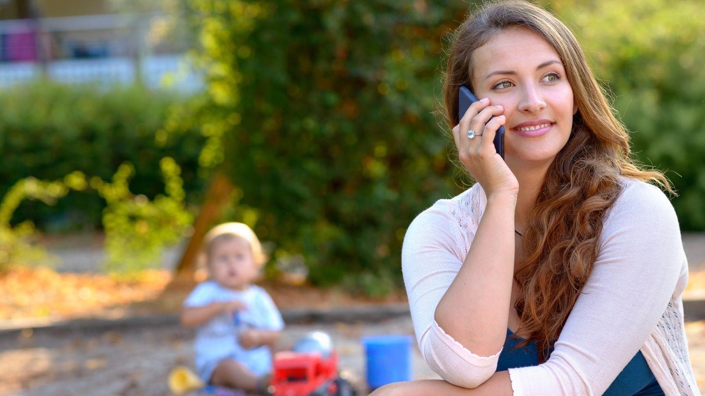 Eine Mutter telefoniert auf dem Spielplatz und sieht ihr Kind nicht