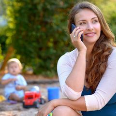 Eine Mutter telefoniert auf dem Spielplatz und sieht ihr Kind nicht