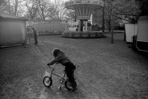 Ein einsames Kind fährt auf einem leeren Rummelplatz Fahrrad