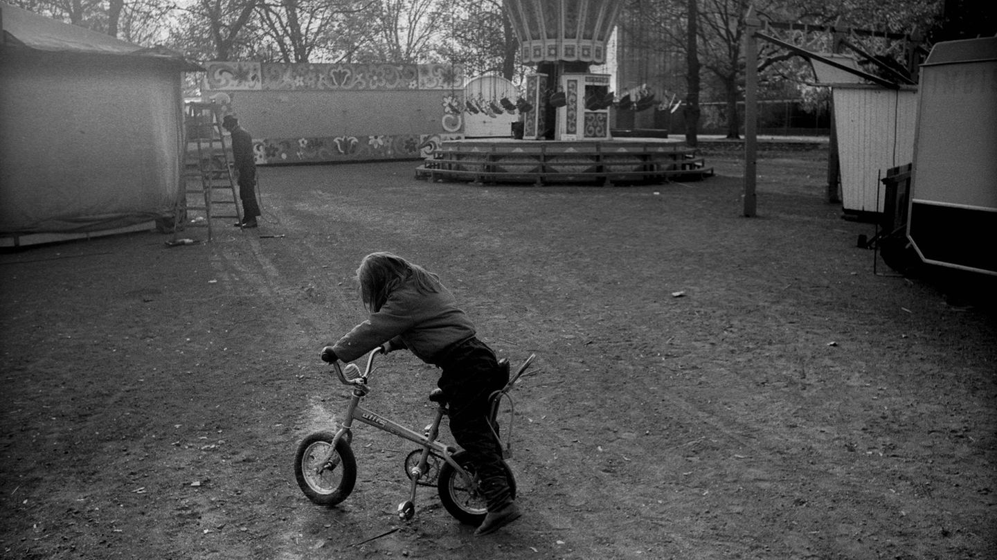 Ein einsames Kind fährt auf einem leeren Rummelplatz Fahrrad