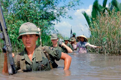 US-Soldat durchquert einen tiefen Bewässerungskanal zusammen mit Mitgliedern der 5th ARVN Ranger Group