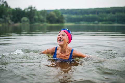 Ältere Frau schwimmt im See und lacht – über die Rentenerhöhung?