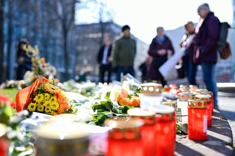 Blumen und Kerzen liegen am Paradeplatz in Mannheim, Menschen halten inne und trauern