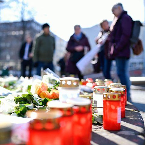 Blumen und Kerzen liegen am Paradeplatz in Mannheim, Menschen halten inne und trauern