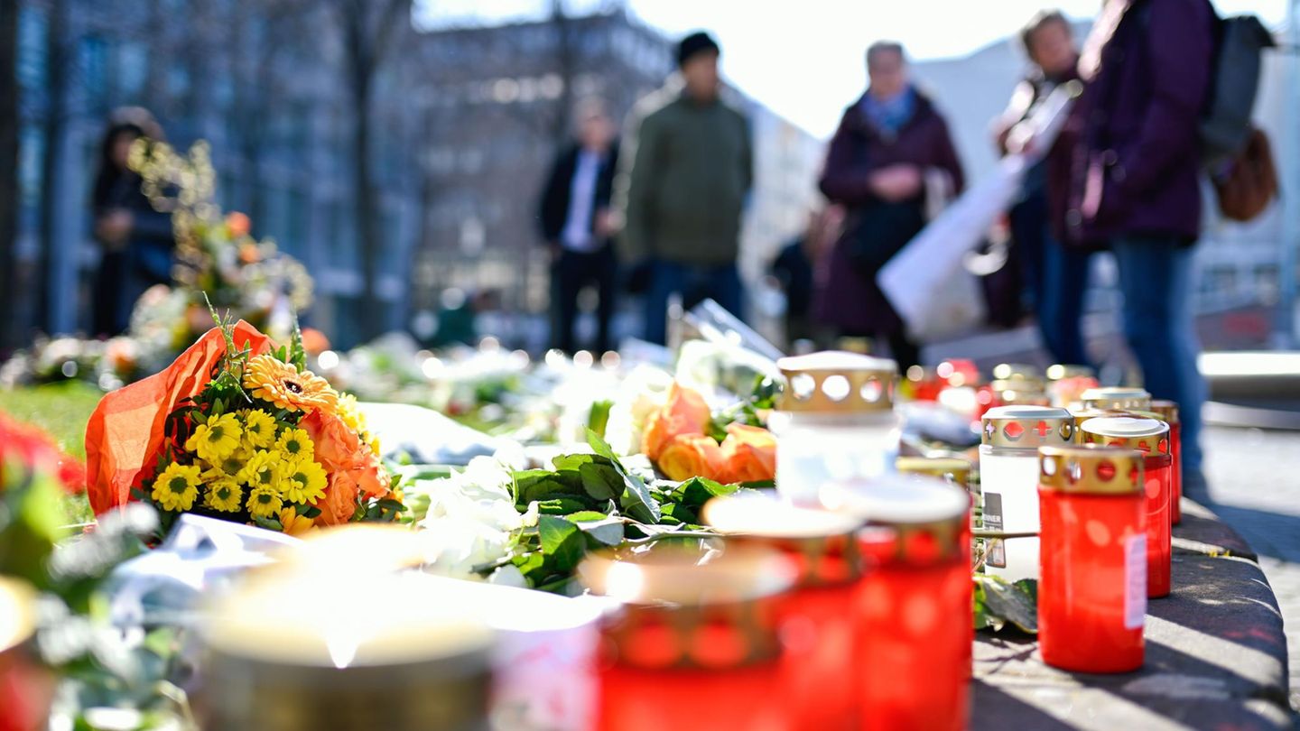 Blumen und Kerzen liegen am Paradeplatz in Mannheim, Menschen halten inne und trauern