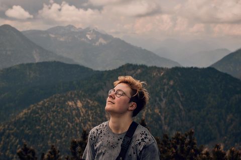 Lennart schließt entspannt die Augen vor einem Bergpanorama