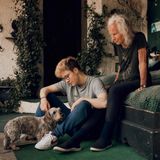 Lennart streichelt einen Dackel, während seine Oma hinter ihm auf dem Bettt sitzt