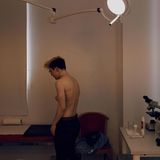 Lennart steht oberkörperfrei im Behandlungszimmer einer Arztpraxis