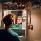 Transmann Lennart steht im Bad vor dem Spiegel und betrachtet sein Kinn