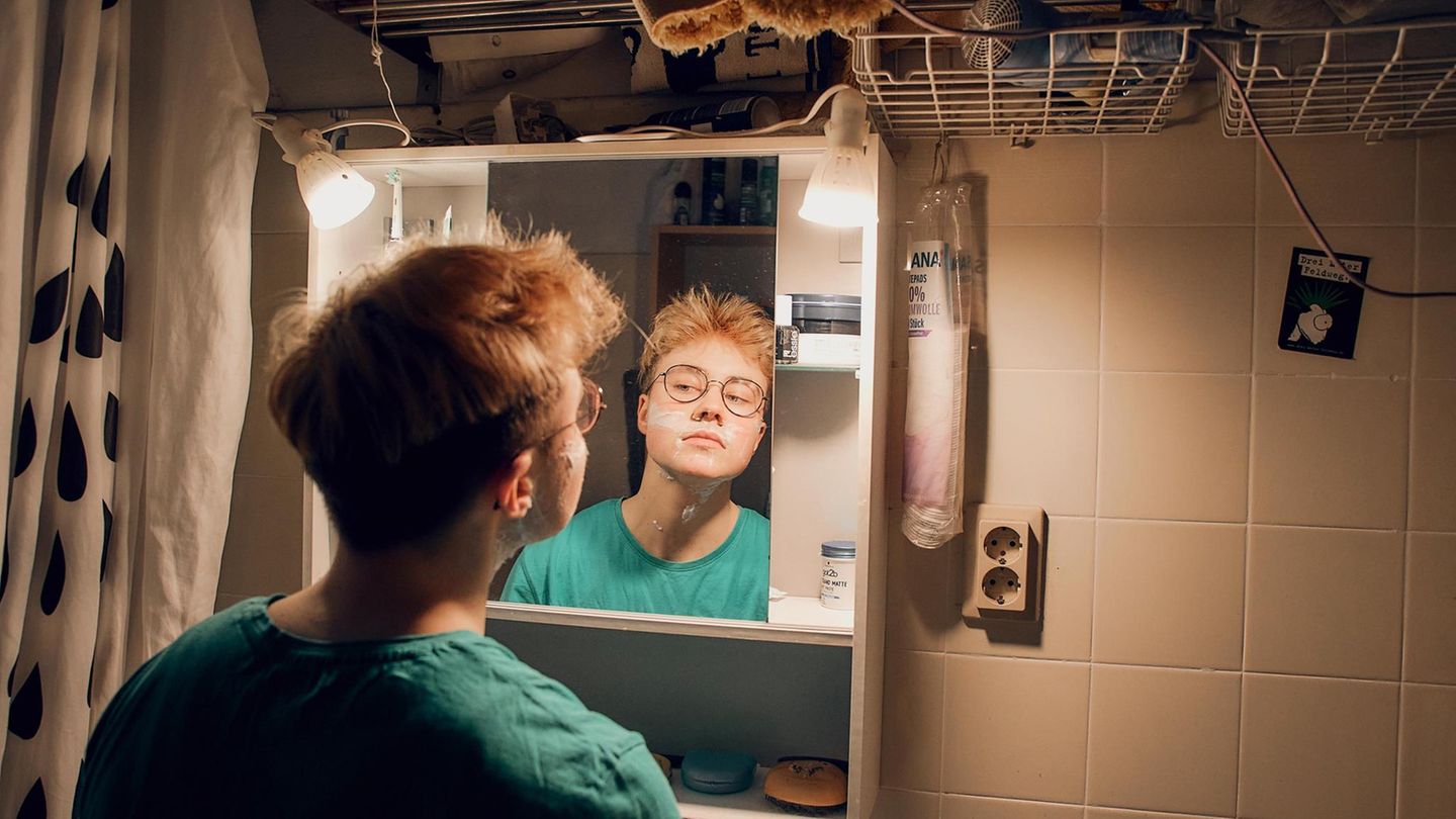 Transmann Lennart steht im Bad vor dem Spiegel und betrachtet sein Kinn