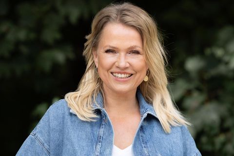 Nova Meierhenrich lächelnd vor einer Hecke