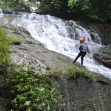 Eine junge Frau seilt sich einen Wasserfall hinab