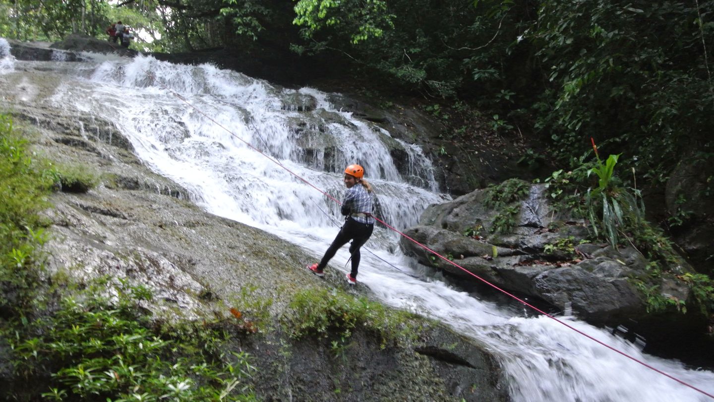 Eine junge Frau seilt sich einen Wasserfall hinab Eine junge Frau seilt sich einen Wasserfall hinab