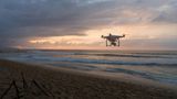 Eine Drohne überfliegt am Abend einen Strand
