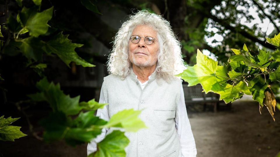 Rainer Langhans: "Ich schwebe über diesem ganzen Dunst von libidinösem Leben" Rainer Langhans steht in weißen Klamotten zwischen Blättern eines Ahornbaumes und blickt in die Ferne