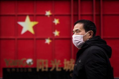 Coronavirus: Momentaufnahme aus Wuhan während der Pandemie. Mann mit Maske vor China-Flagge