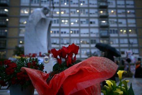Blumen für Franziskus vor der Statue von Papst Johannes Paul II. vor der Klinik in Rom