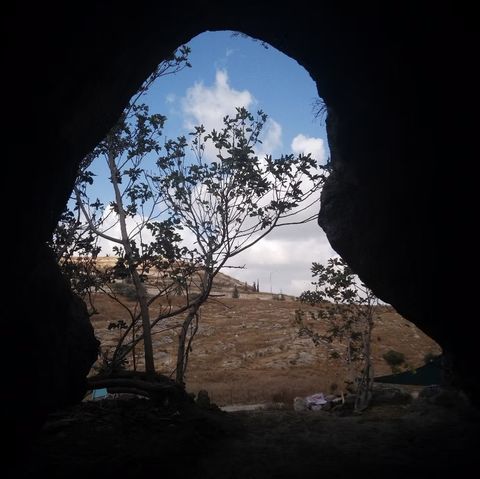 Neandertaler: Blick aus einer dunklen Höhle in Israel ins Freie, auf eine karge Ebene und Himmel