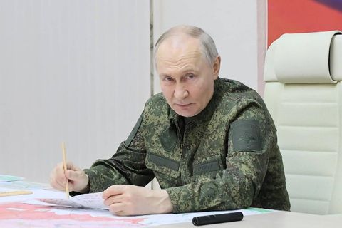 Wladimir Putin sitzt in einem Camouflage-Anzug an einem Schreibtisch