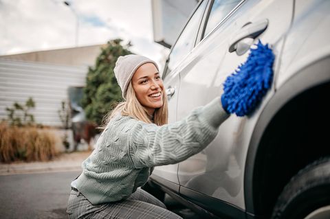 Eine Frauen reinigt ihr Auto mit Wischtuch