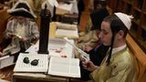 Jüdische ultraorthodoxe Männer und Kinder, von denen einige Kostüme tragen, lesen in der Synagoge