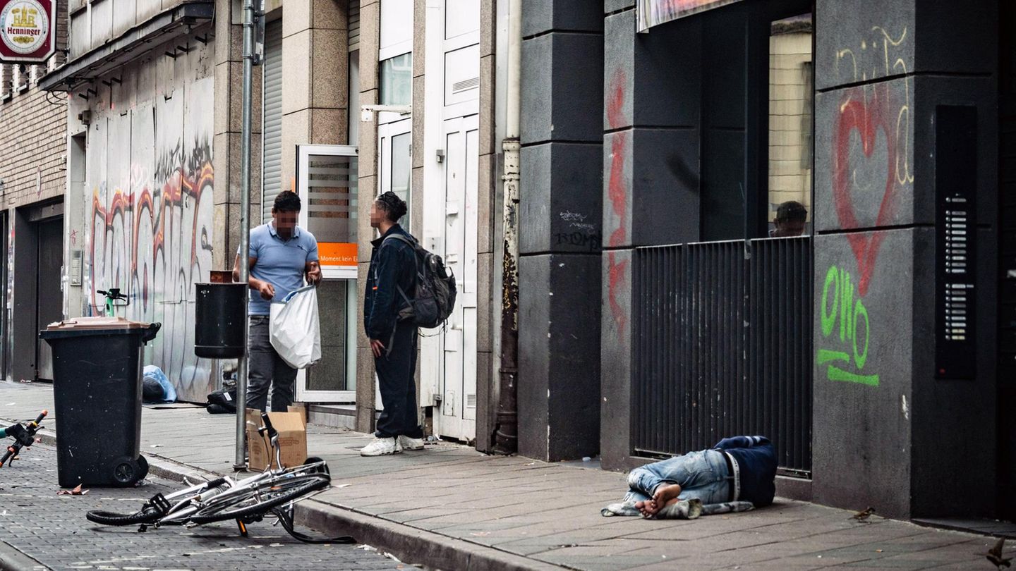 Zwei Männer stehen auf der Straße, einer liegt auf dem Asphalt im Frankfurter Bahnhofsviertel