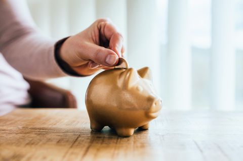Abikasse für Abifeier Symbolbild: Ein goldenes Sparschwein, eine Hand steckt eine Münze hinein