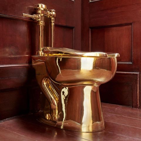 Eine Toilette aus 18-karätigem Gold steht in einer dunkel vertäfelten Ecke
