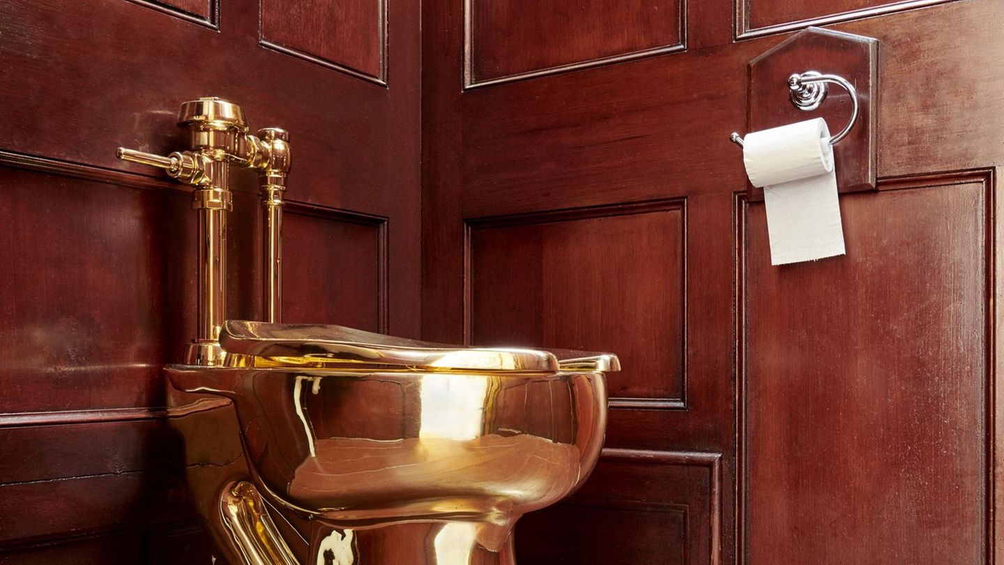Eine Toilette aus 18-karätigem Gold steht in einer dunkel vertäfelten Ecke