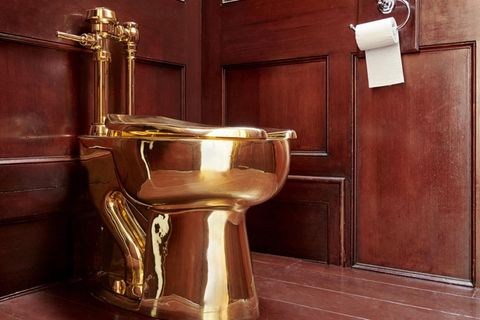 Eine Toilette aus 18-karätigem Gold steht in einer dunkel vertäfelten Ecke