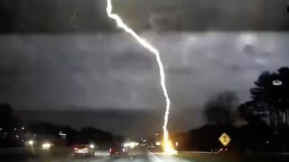 Ein Blitz schlägt auf einer Fahrbahn kurz vor dem filmenden Auto ein
