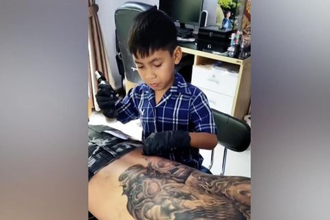 Der neunjährige Napat Mitmakorn tätowiert den Rücken eines Mannes großflächig