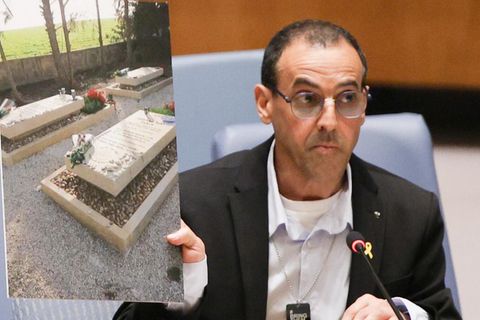 Eli Sharabi vor dem Sicherheitsrat, wo er in Bild von den Gräbern seiner von de Hamas ermordeten Familie hochhält