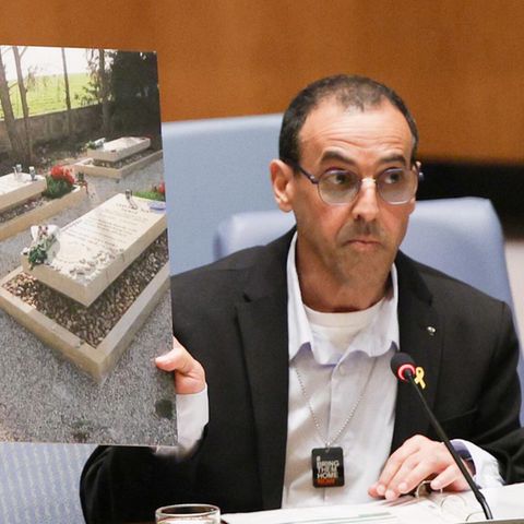 Eli Sharabi vor dem Sicherheitsrat, wo er in Bild von den Gräbern seiner von de Hamas ermordeten Familie hochhält