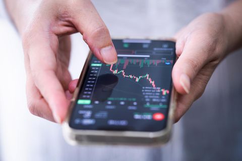 Eine Frau checkt den Aktienkurs auf ihrem Handy