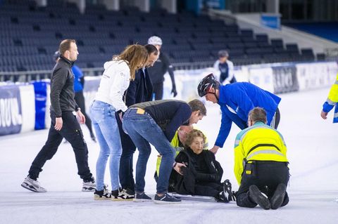 Prinzessin Margriet sitzt umringt von Helfern auf der Eisfläche in einem Stadion