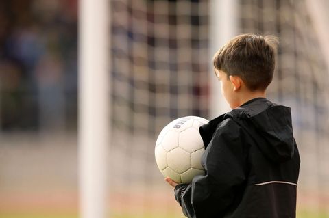 Balljunge mit Fußball in den Händen vor einem Fußballtor (Symbolbild)