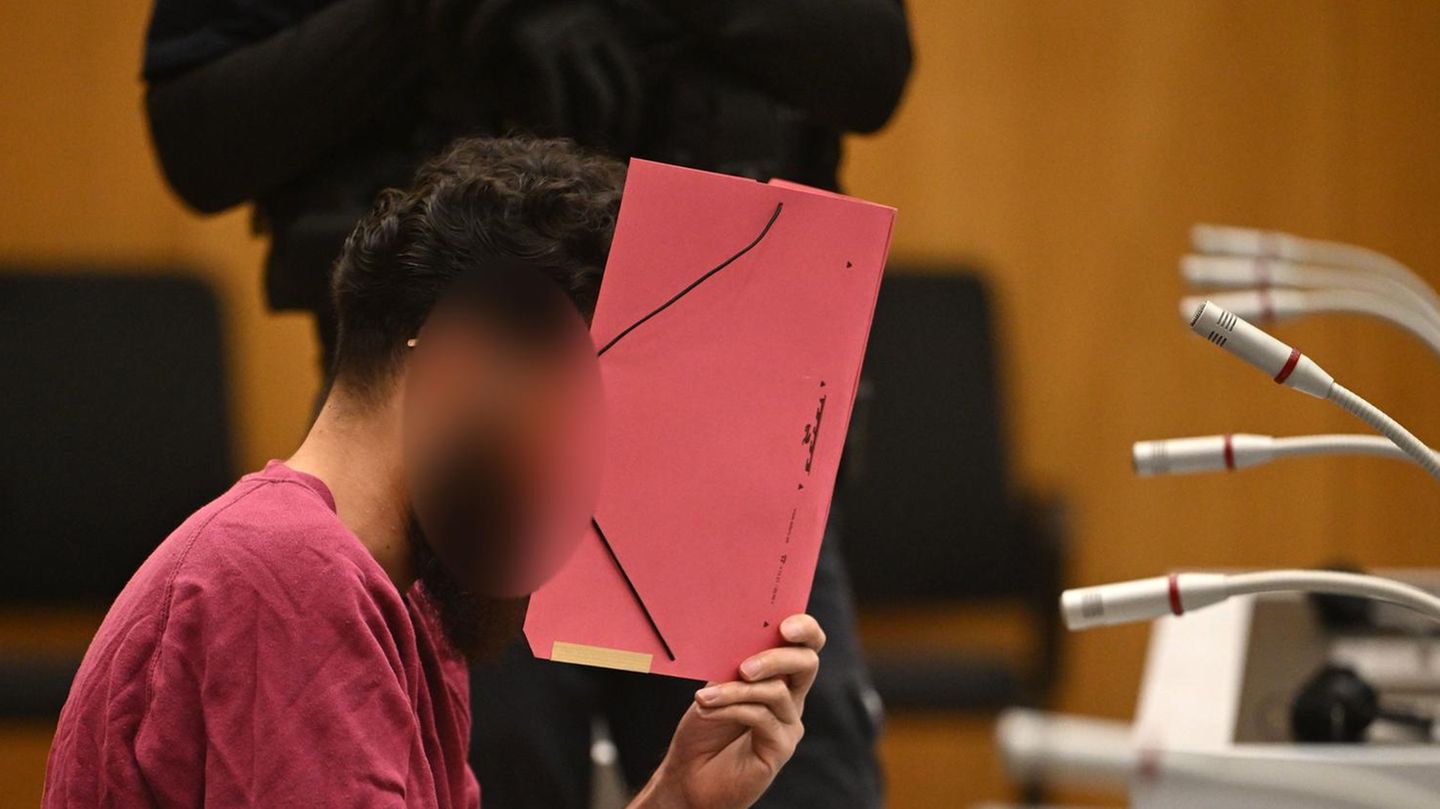 Der Angeklagter wegen der Messerattacke in Mannheim verbirgt im Gericht sein Gesicht mit einem roten Pappordner
