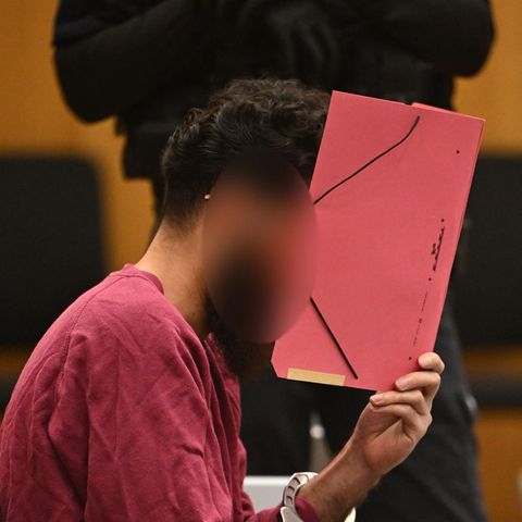 Der Angeklagter wegen der Messerattacke in Mannheim verbirgt im Gericht sein Gesicht mit einem roten Pappordner