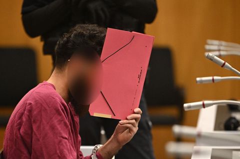 Der Angeklagter wegen der Messerattacke in Mannheim verbirgt im Gericht sein Gesicht mit einem roten Pappordner