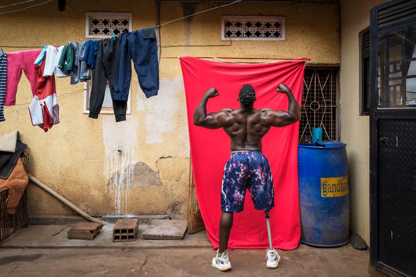 Gewinnerin Afrika: Marijn Fidder Bodybuilder Tamale Safalu steht vor einer Wand und hebt die Arme nach oben.