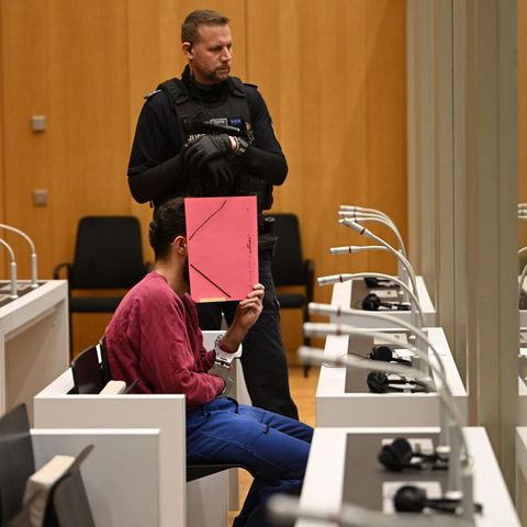 Der mutmaßliche Messerattentäter von Mannheim sitzt im Gerichtssaal und verdeckt sein Gesicht mit einem Ordner.